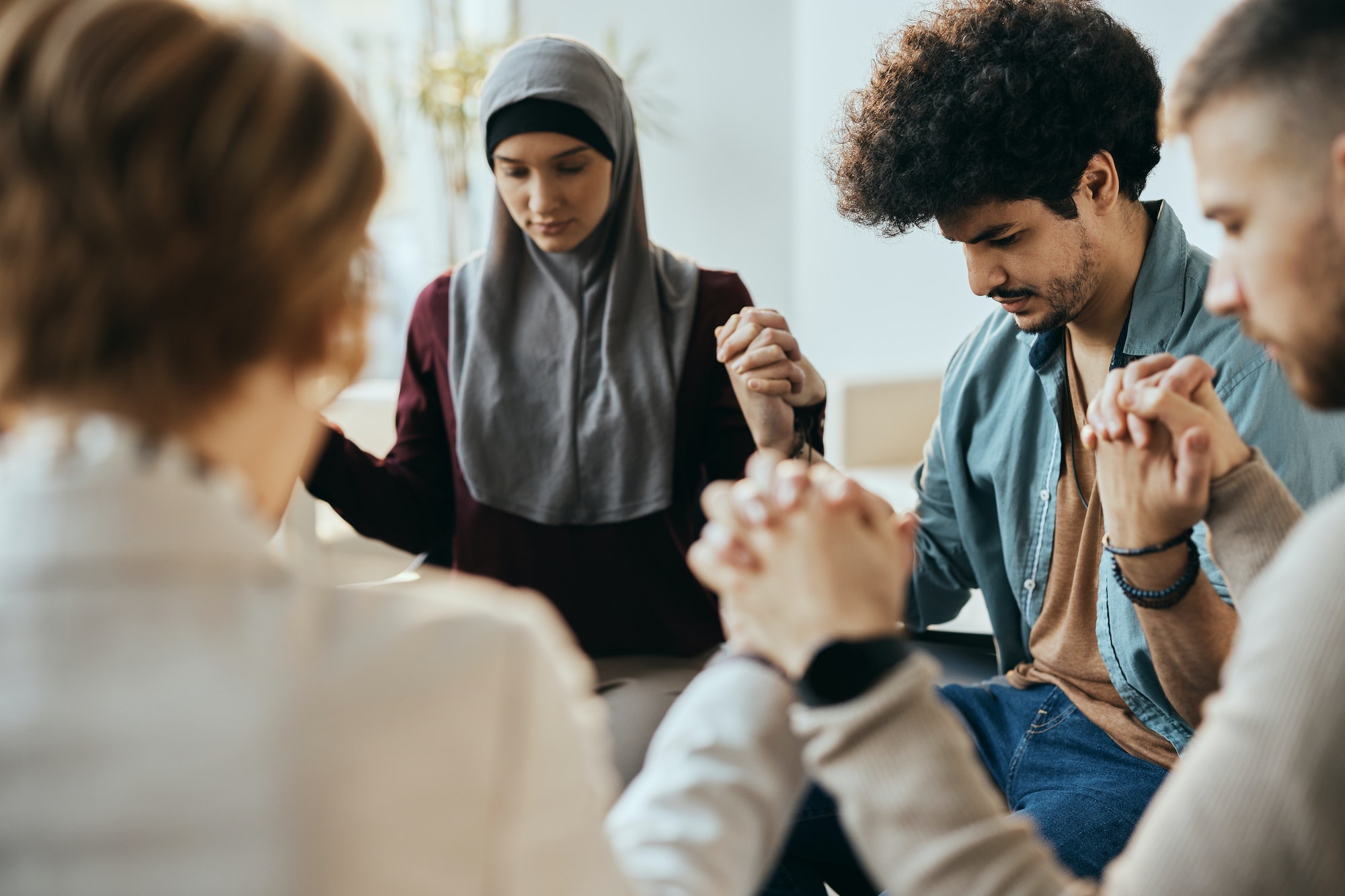 multi-ethnic-attenders-of-group-therapy-holding-hands-during-counseling-at-mental-health-center-.jpg